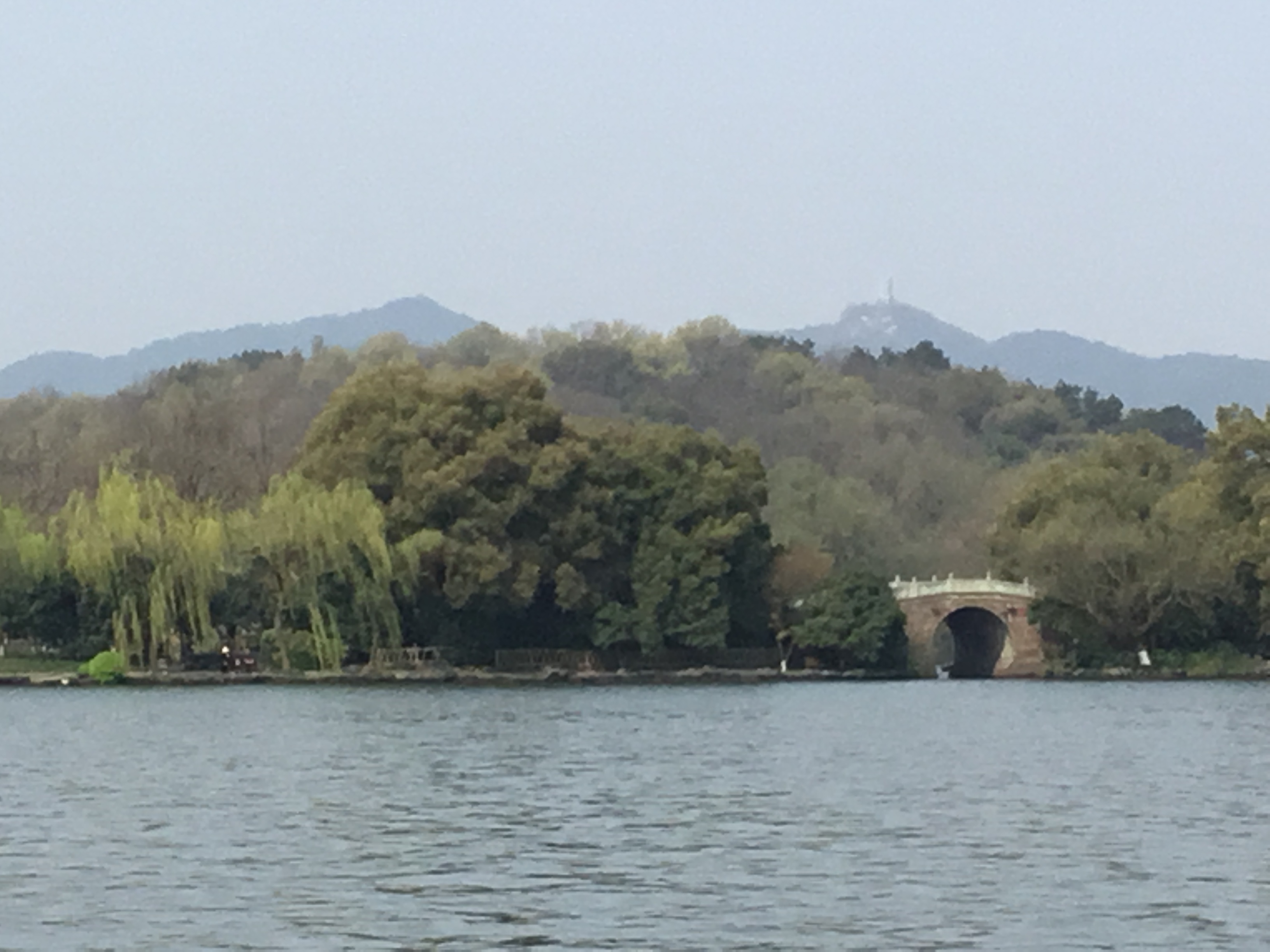A causeway crossing West Lake with the Hangzhou hills behind it